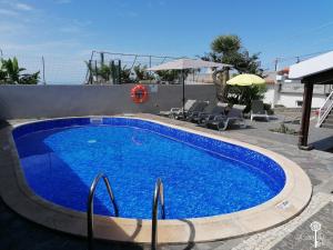 a large blue swimming pool with chairs and an umbrella at Casa da Edite in Ponta do Sol