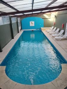 una piscina con sillas en un edificio en Hotel San Remo Majestic en Mar de Ajó