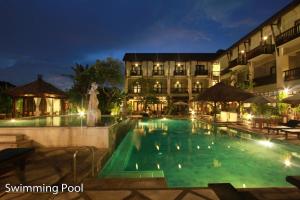 The Lokha Legian Resort & Spa في ليغِيان: مسبح امام الفندق في الليل