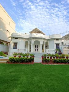 a large white house with a lawn in front of it at Homestay at Bungalow 97 Ajmer in Ajmer