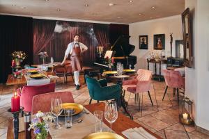 a man standing in a room with tables and a piano at Boutiquehotel Liebesglück - adults only in Winterberg