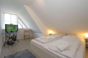 Cama blanca en habitación con ventana en Haus-Suedstrand-Appartement-12, en Westerland