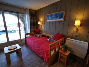 Schlafzimmer mit einem roten Bett und einem TV in der Unterkunft Meribel Le Creux de l'Ours in Les Allues