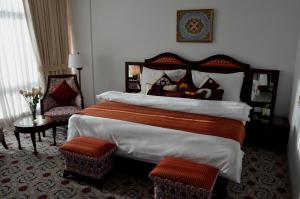 a hotel room with a large bed and a chair at Dushanbe Serena Hotel in Dushanbe