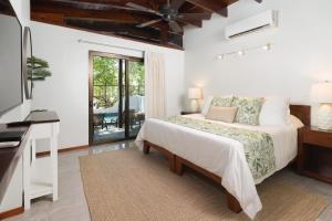 a bedroom with a bed and a desk and a television at Casa Woodbine Private House on Tamarindo Beach in Tamarindo