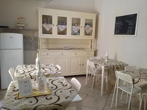 a kitchen with tables and chairs and a refrigerator at Il Sole del Mediterraneo in Noto