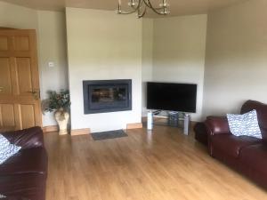 sala de estar con 2 sofás y TV de pantalla plana en Tranquil Modern Countryside Bungalow, en Dungannon