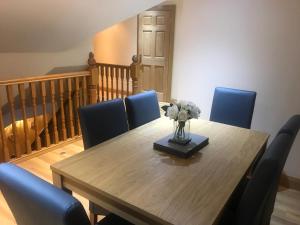 una mesa de comedor con sillas azules y un jarrón con flores en Tranquil Modern Countryside Bungalow, en Dungannon