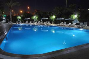 a large blue pool with chairs and umbrellas at night at Villa with pool near the sea in Konaklı