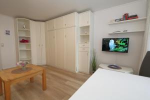 ein Wohnzimmer mit weißen Schränken und einem TV an der Wand in der Unterkunft Haus am Meer App. 71 in Westerland