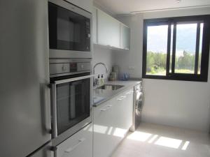 a white kitchen with a sink and a microwave at City Apt - Sleeps 4 Community Pool & Parking in Denia