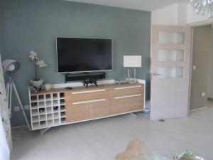 una sala de estar con TV en un centro de entretenimiento de madera en Modern apartment close to centre of Denia Spain en Dénia