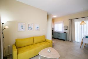 a living room with a yellow couch and a table at Varkes Suites 1 in Nea Potidaea