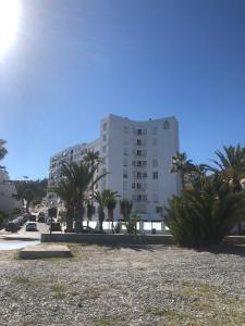 a large white building with palm trees in front of it at Velilla Park 2 Playa in Almuñécar