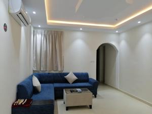 فخامة الارجوانة للأجنحة الفندقية في محافظة سكاكا: غرفة معيشة مع أريكة زرقاء وطاولة