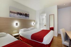 a hotel room with two beds and a table at Hôtel LUX PICPUS in Paris