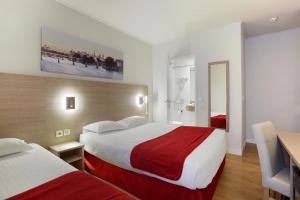 Habitación de hotel con 2 camas y mesa en Hôtel LUX PICPUS, en París