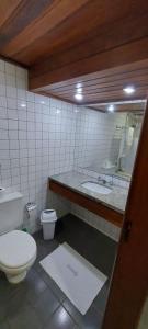 a bathroom with a toilet and a sink and a mirror at Sol Victoria Marina Flat in Salvador