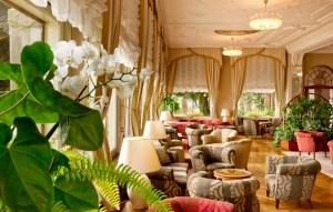a lobby with couches and chairs and plants at Grand Hotel Gardone in Gardone Riviera