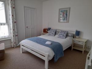 a bedroom with a bed with a blue blanket and pillows at 'Pavilion Cottage' next to Gorleston beach with sea views - pet friendly! in Gorleston-on-Sea