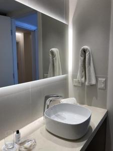 Baño blanco con lavabo y espejo en Terrazas Al Mar en Pinamar