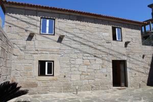 a stone building with three windows and a door at Alojamento Local Boega Hotel - Casas Boega I e II in Gondarém