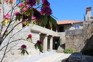 a building with pink flowers on a tree at Alojamento Local Boega Hotel - Casas Boega I e II in Gondarém
