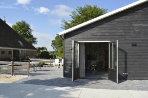 a black building with a door open to a patio at Woudmeer 1 in Dirkshorn