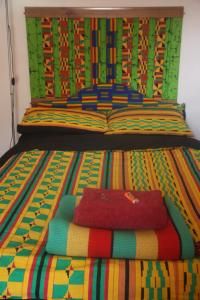 a bed with a colorful striped comforter on it at Bradford Digs in Bradford