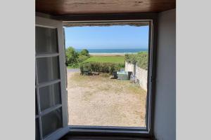 uma janela aberta com vista para um pátio em SCIOTOT - Bord de mer - La petite maison em Les Pieux