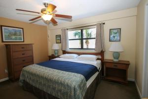 Schlafzimmer mit einem Bett, einem Deckenventilator und einem Fenster in der Unterkunft All Seasons Vacation Resort by Libertè in St Pete Beach + 148 Fotos