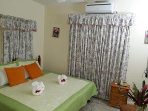 sypialnia z zielonym łóżkiem z 2 białymi chusteczkami w obiekcie Paradise Inn w mieście Port Antonio