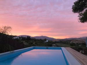 une piscine avec vue sur le coucher du soleil en arrière-plan dans l'établissement La Hermosa Vista, à Alora