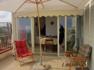 einen Regenschirm auf einer Veranda mit 2 Stühlen und einem Tisch in der Unterkunft Attico Con Vista Panoramica Sul Mare in Sciacca