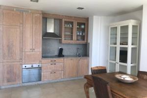 cocina con armarios de madera y mesa de madera en Apartamento primera línea de playa, en Finisterre