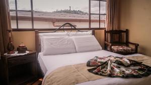 1 dormitorio con 1 cama blanca y ventana en Hotel La Cierva de San Marcos, en Quito