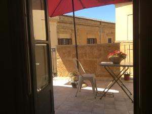 a table and chair on a balcony with an umbrella at Charme in centro - Tourist rental in Agrigento