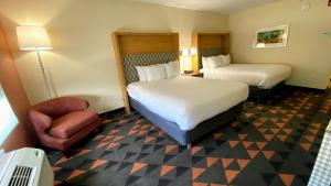 una habitación de hotel con 2 camas y una silla en Holiday Inn Spartanburg Northwest, en Spartanburg