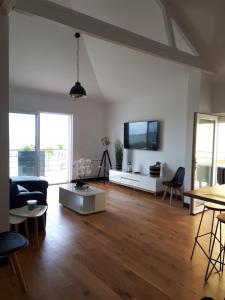 a living room with a couch and a tv at Maison et grande terrasse face mer in Saint-Michel-Chef-Chef