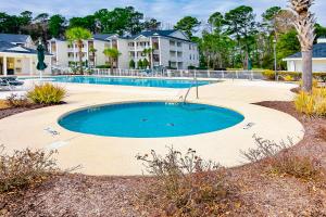 a swimming pool in a yard with houses in the background at River Oaks Retreat in Myrtle Beach