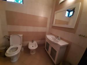 een badkamer met een toilet, een wastafel en een spiegel bij Fiori Apartment in Gevgelija