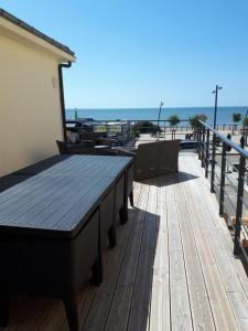 eine Holzterrasse mit Tischen und Stühlen am Strand in der Unterkunft Maison et grande terrasse face mer in Saint-Michel-Chef-Chef
