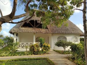 ein großes weißes Haus mit einem Strohdach in der Unterkunft Neverland Watamu Villas in Watamu