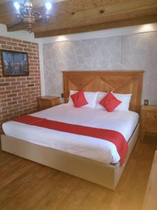 1 dormitorio con 1 cama grande con almohadas rojas en Hotel Rincon Del Real, en Mineral del Monte