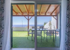 a dining room with a table and chairs and a view of the ocean at Flowers island house 3 in Caniço