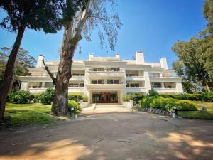 a large white building with a tree in front of it at Green Park 2 Ambientes con Balcón Vista Bosque o Laguna con Parrillero in Punta del Este