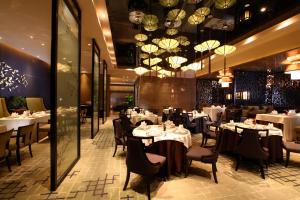 a restaurant with white tables and chairs and chandeliers at Tangla Hotel Tianjin in Tianjin