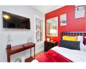 a bedroom with a red wall with a bed and a desk at Cozy Downtown Studio by Toyota Center in Houston