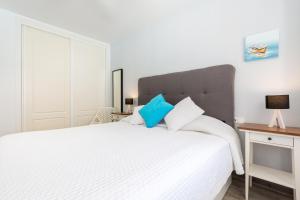 a bedroom with a large white bed with blue pillows at Casa Wind in Costa Calma