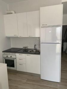 a white kitchen with a refrigerator and a sink at Apartamentos BEACHYDAYS Montalvo in Torremolinos